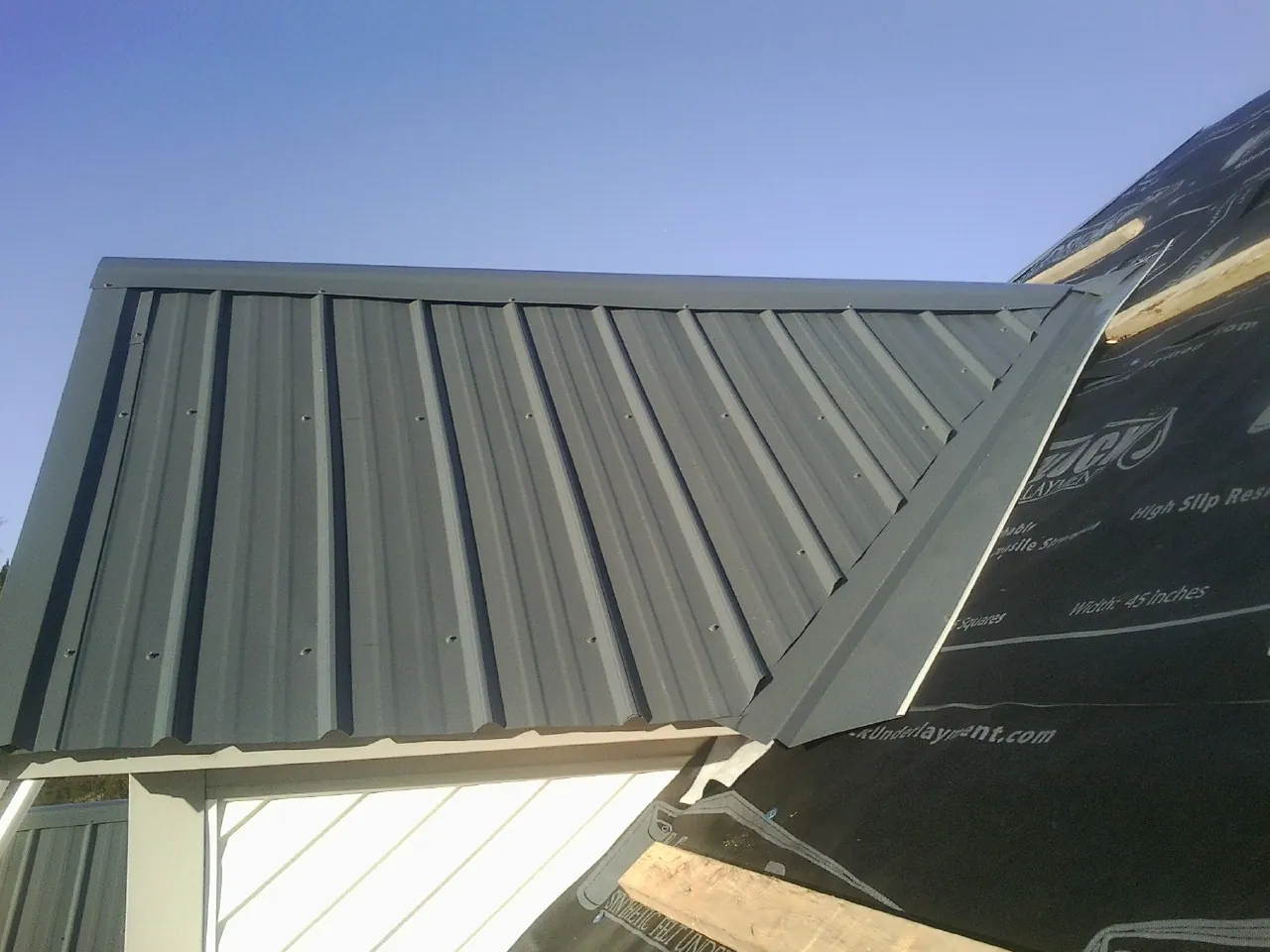 Gray metal roof panels going on over a garage gable in Dilliner