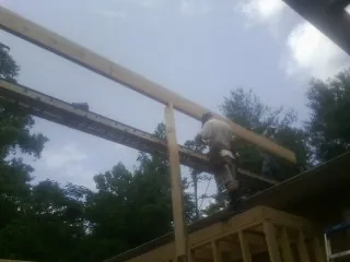 Carpenter setting a ridge beam over a new addition frame — Ice Dam Removal by Roofing Brothers in Dilliner