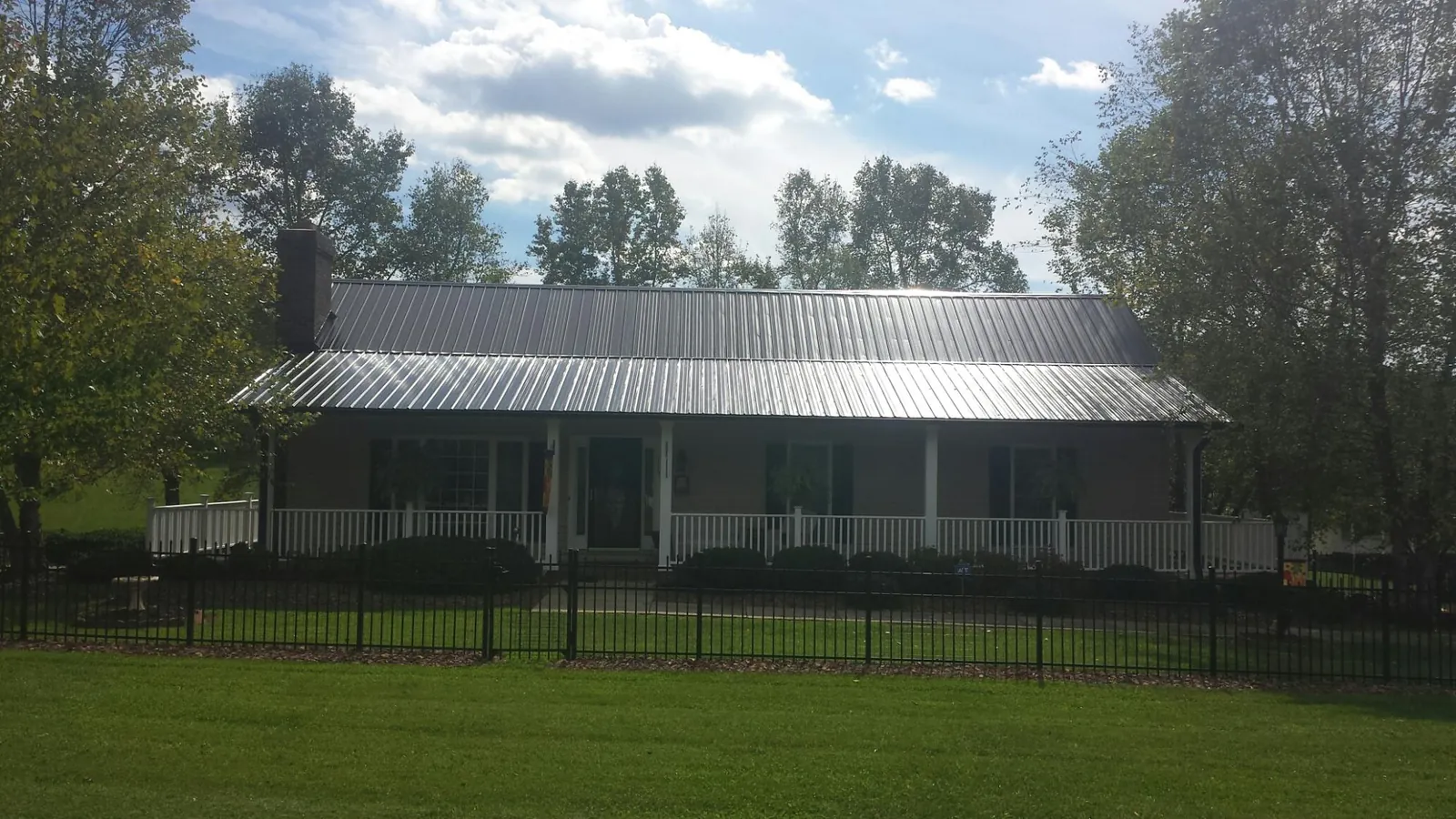 Gray metal roof on a brick ranch with a full width front porch — Gutter Guard Installation work by our crew in Dilliner