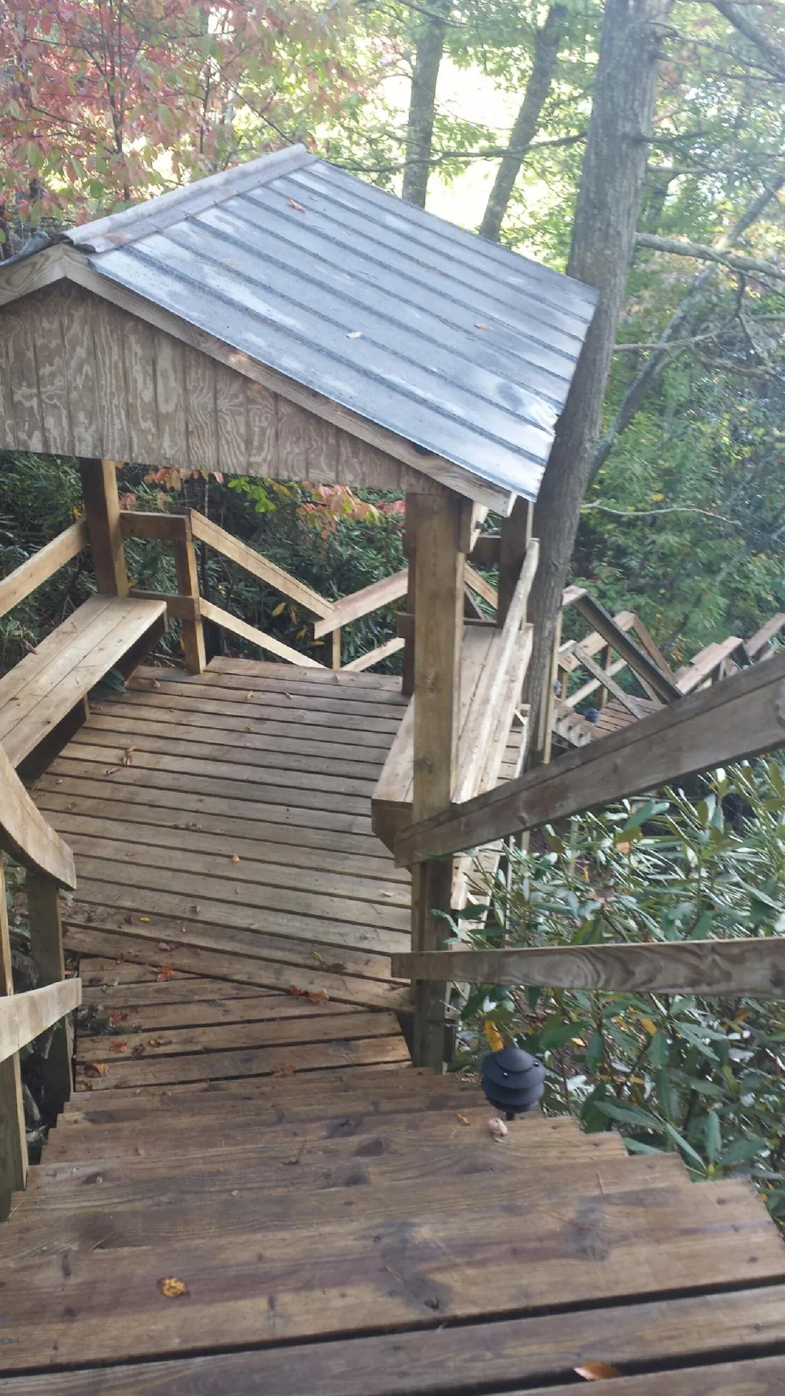 Metal roofed shelter over wooden steps on a wooded walkway — Skylight Repair & Installation work by our crew in Dilliner