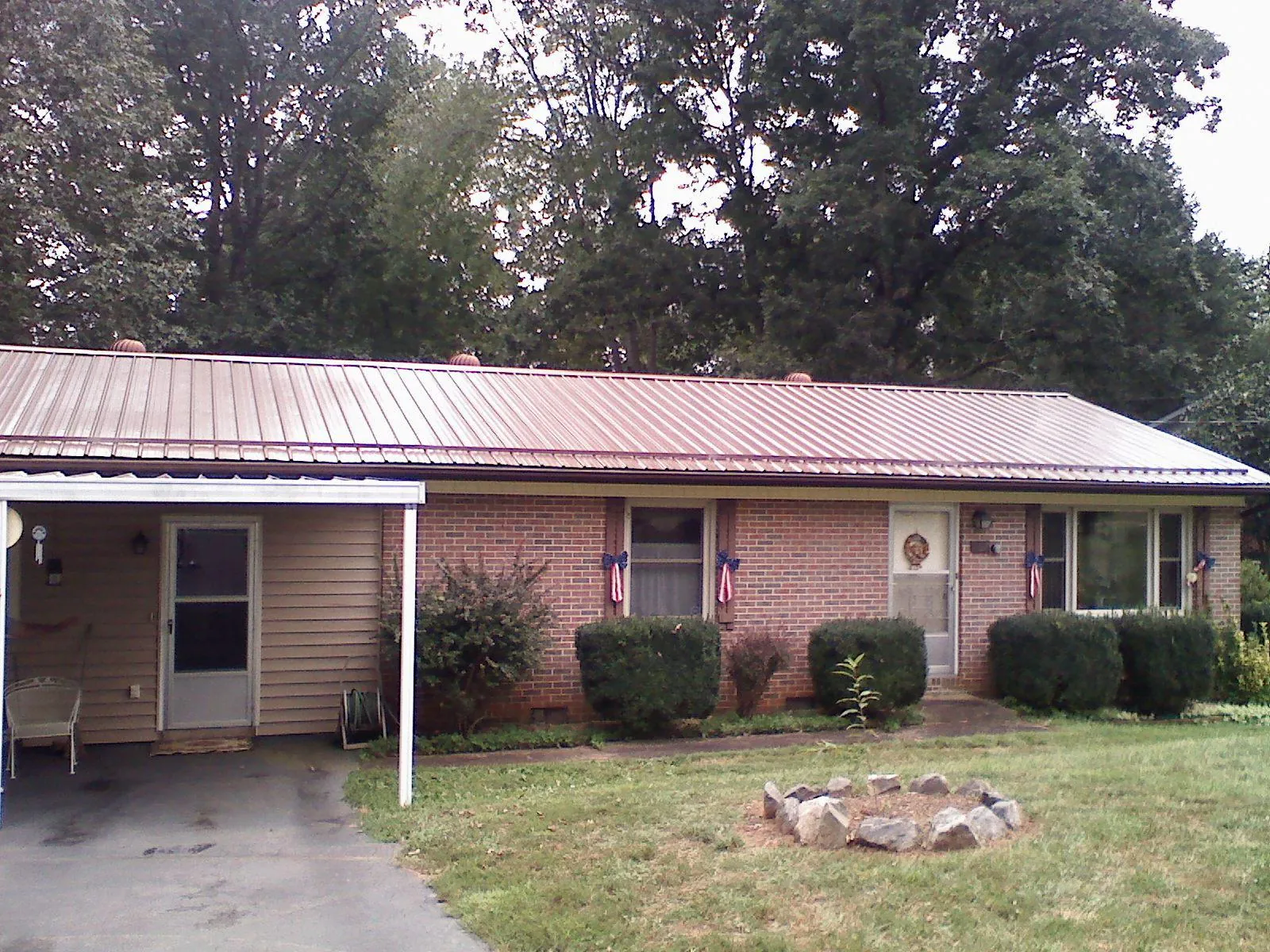 Bronze metal roof and carport on a brick ranch home — Roof Repair work by our crew in Dilliner