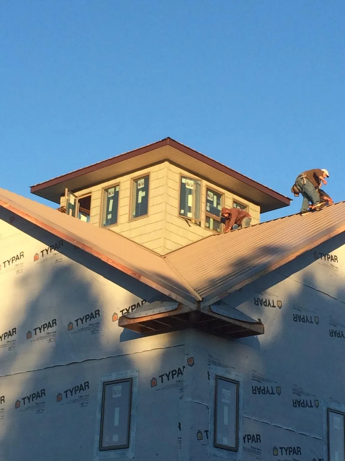 Roofers working around a rooftop cupola on a new metal roof at sunset — Roof Waterproofing in Dilliner by Roofing Brothers